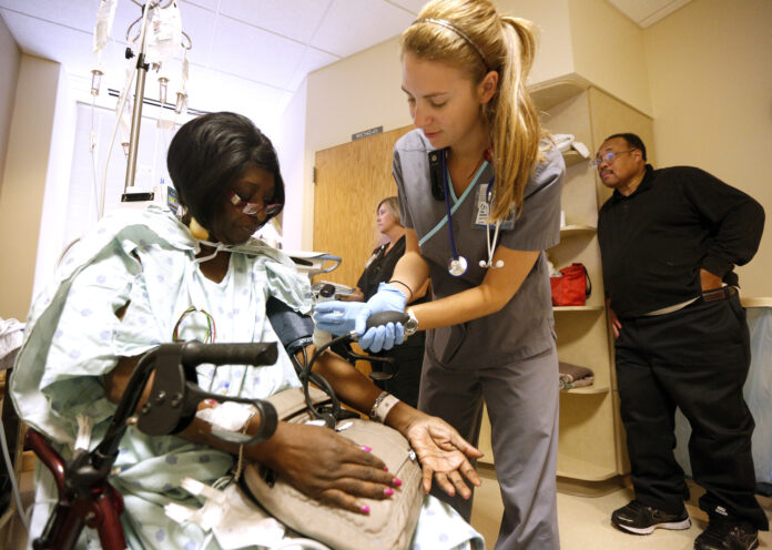 Registered nurse Paige Duracher checks Jacqueline Parker's vitals in the cardiac step-down area of the University of Mississippi Medical Center in Jackson, Mississippi